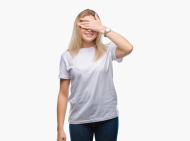 Genç gülümseyen ve gözler için sürpriz kapsayan yüz el ile gülüyor izole arka plan beyaz kadın. Kör kavramı.