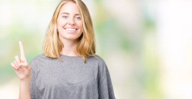 Ve parmak gülümseyen süre bir numara ile kendinden emin ve mutlu yukarıyı gösteren izole arka plan üzerinde büyük boy rahat t-shirt giyen güzel genç kadın.