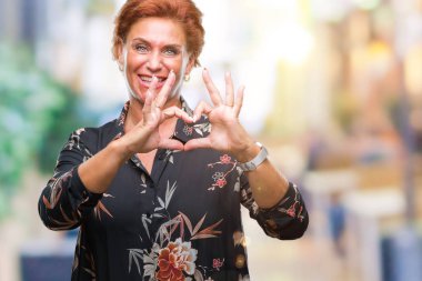 Atrractive üst düzey beyaz Kızıl saçlı kadın kalp simgesi ve elleriyle şekil gösterilen aşık gülümseyen izole arka plan yüzünden. Romantik kavramı.