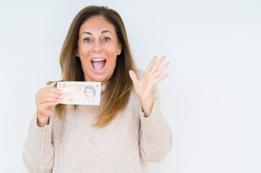 10 pound banknot büyük gülümseme ile çığlık zaferini kutluyor ve ellerini kaldırdı izole arka plan çok mutlu ve heyecanlı, kazanan ifade üzerinde tutan orta yaş kadın