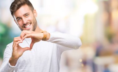 Yakışıklı delikanlı aşık kalp simgesi ve elleriyle şekil gösteren gülümseyen izole arka plan üzerinde. Romantik kavramı.