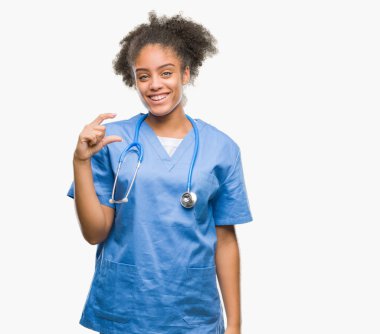 Genç afro Amerikalı doktor kadın izole arka plan gülümseyen ve boyutu işaret parmaklı ararken ve kamera işi el ile kendine güvenen el hareketi yüzünden. Ölçü kavramı.