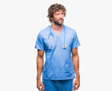 Yakışıklı İspanyol cerrah doktor adam seksi bir ifadeyle, neşeli ve mutlu yüzünü kameraya bakarak göz kırpıyor izole arka plan.