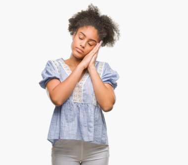 Uyku yorgun hayal ve ellerle birlikte poz ile kapalı gözler gülümseyen izole arka plan üzerinde genç afro Amerikalı kadın.