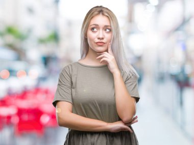 Genç Sarışın kadın elle çene düşünme hakkında soru, dalgın ifade izole arka plan yüzünden. Düşünceli yüzüyle gülümsüyor. Şüphe kavramı.