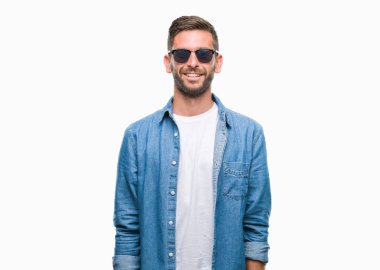 Genç yakışıklı adam yüzünde mutlu ve güzel bir gülümseme ile izole arka plan üzerinde güneş gözlüğü takıyor. Şanslı kişi.