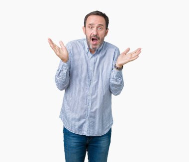 Yakışıklı orta yaş izole arka plan clueless ve şaşkın bir ifadeyle kollar ve eller kaldırdı üzerinde zarif komuta sizde. Şüphe kavramı.