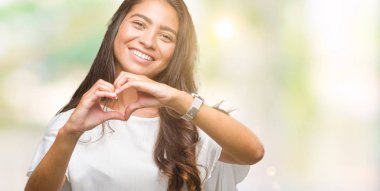 Genç güzel Arap kadın kalp simgesi ve elleriyle şekil gösterilen aşık gülümseyen izole arka plan yüzünden. Romantik kavramı.