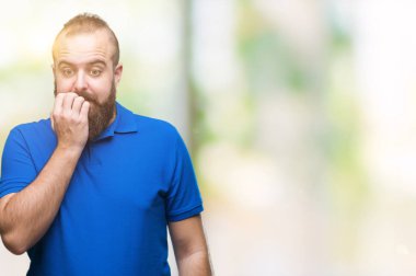 Genç beyaz hipster adam stresli ve gergin elle çivi ısırma ağzına bakarak izole arka plan üzerinde mavi tişört giyiyor. Anksiyete sorunu.