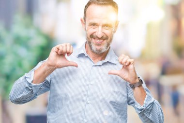 Orta yaş ağarmış üst düzey iş adamı yüzünde gülümseme ile kendinden emin görünüyorsun, kendini gururlu ve mutlu parmakları ile işaret izole arka plan üzerinde.