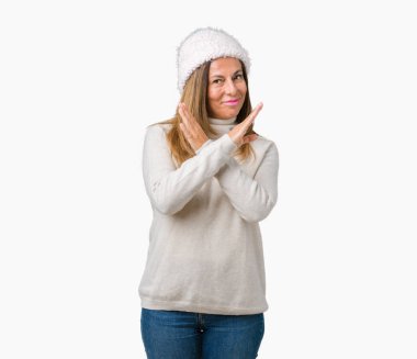 İzole arka plan ret ifade geçiş kollarına eksi işareti, kızgın surat yapıyor kış kazak ve şapka giyen güzel orta yaş kadın