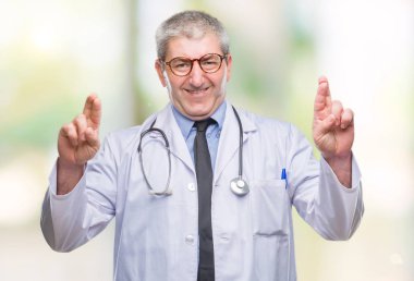 Umut ve gözleri kapalı geçiş parmaklarıyla gülümseyen izole arka plan yakışıklı kıdemli Doktor adam. Şans ve batıl kavramı.