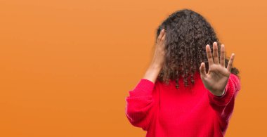 Kırmızı kazaklı kapsayan giyen genç İspanyol kadın gözleri ile el ve stop jest ile acı ve korku ifadesi. Utandım ve negatif kavramı.