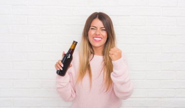 Beyaz tuğla duvar holding bira rahatsız Yound yetişkin kadın ve boşa çıkarmak ile öfke, çılgın ve yükseltilmiş eliyle diye bağıran öfke kavramı bağırarak.