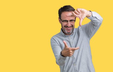 Elle yapma çerçeve ve parmakları ile mutlu yüz gülümseyen izole arka plan üzerinde gözlük takan yakışıklı orta yaş zarif komuta sizde. Yaratıcılık ve Fotoğrafçılık kavramı.