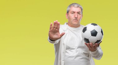 Üst düzey yakışıklı açık eliyle dur işareti ile ciddi ve kendine güvenen ifade, savunma jest yapıyor izole arka plan üzerinde futbol futbol topu tutan