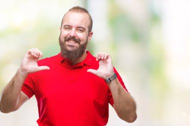 Yüzünde gülümseme ile kendinden emin görünüyorsun, kendini gururlu ve mutlu parmakları ile işaret izole arka plan üzerinde kırmızı gömlek giyen genç beyaz hipster adam.