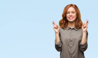 Umut ve gözleri kapalı geçiş parmaklarıyla gülümseyen izole arka plan üzerinde genç güzel kadın. Şans ve batıl kavramı.