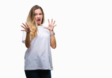 Şokta bağırarak korkuyor ve dehşet korku ifade dur hareketi el ile ile izole arka plan üzerinde rahat beyaz t-shirt giyen genç güzel sarışın kadın. Panik kavramı.