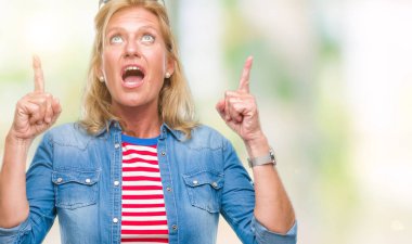 Orta yaş sarışın kadın izole arka plan üzerinden hayran ve yukarıya bakıp parmakları ile işaret şaşırttı ve silah kaldırdı.