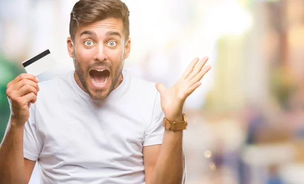 Joven Hombre Guapo Sosteniendo Tarjeta Crédito Sobre Fondo Aislado Muy —  Fotos de Stock