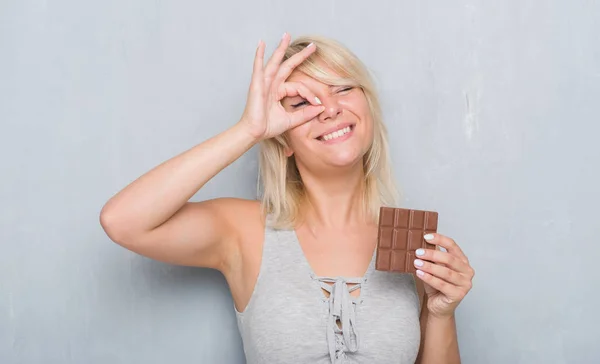 Kaukasische Erwachsene Frau Über Der Grauen Grunge Wand Die Schokoriegel — Stockfoto