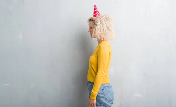 Jovem Loira Sobre Grunge Parede Cinza Usando Chapéu Aniversário Olhando — Fotografia de Stock