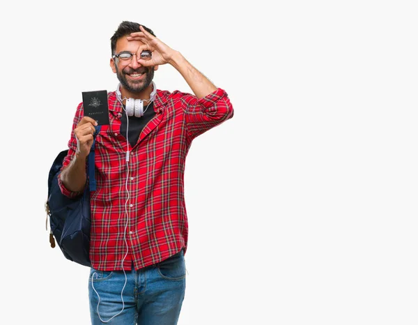 指の間から見て目に手で サインをして笑っている幸せそうな顔で孤立した背景にオーストラリアの大人のヒスパニック学生男持株パスポート — ストック写真