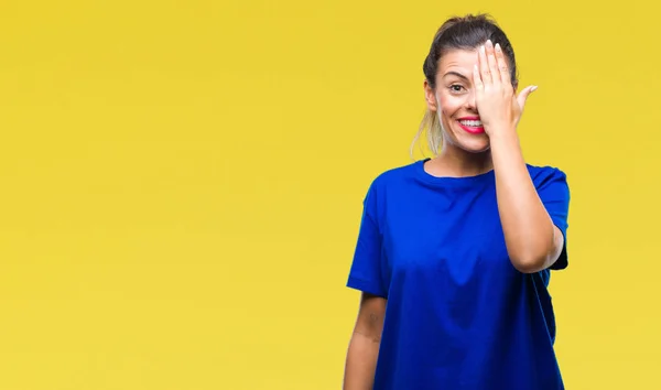 年轻的美女穿着休闲蓝色 T恤在孤立的背景覆盖一只眼睛用自信的微笑在脸上和惊喜的情感 — 图库照片