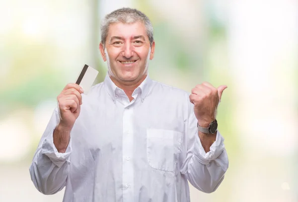 Pěkný Starší Muž Drží Kreditní Karty Nad Izolované Pozadí Ukazuje — Stock fotografie