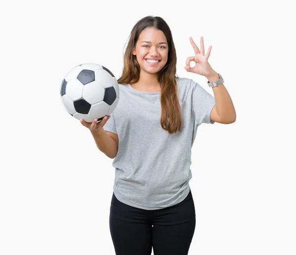 年轻美丽的黑发女子拿着足球在孤立的背景做确定的标志用手指 优秀的标志 — 图库照片