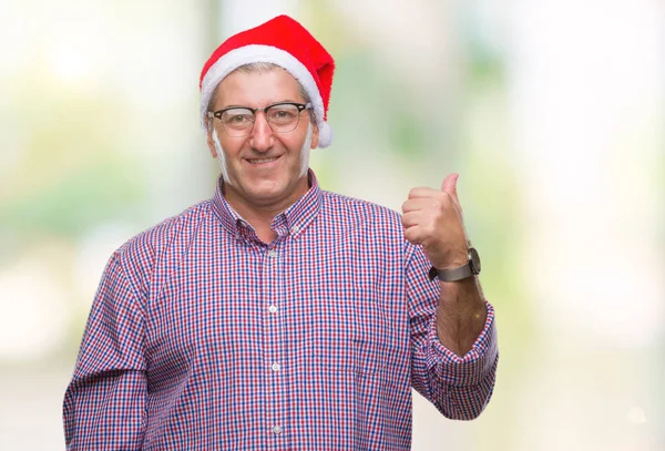 探していると親指側に上向きの幸せそうな顔を浮かべて隔離された背景にクリスマスの帽子を着てハンサムな年配の男性 — ストック写真