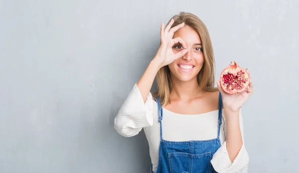 Vacker Ung Kvinna Över Grunge Grå Väggen Hålla Granatäpple Med — Stockfoto