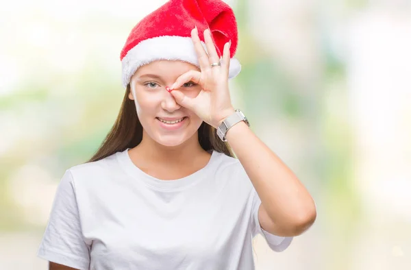 年轻美丽的白人妇女戴着圣诞节帽子在孤立的背景做 手势与手微笑 眼睛看通过手指与幸福的脸 — 图库照片