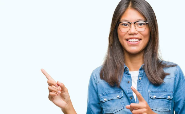 眼鏡をかけて分離背景笑顔で側に つの手と指で指しているカメラ目線の上若いアジア女性 — ストック写真
