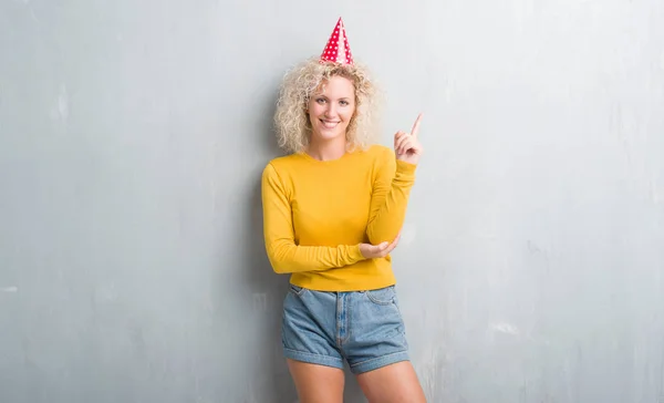 Junge Blonde Frau Über Grunge Grauer Wand Mit Geburtstagsmütze Mit — Stockfoto