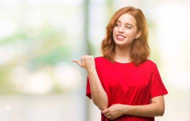 Seyir ve başparmak yanında yukarıyı mutlu yüz ile gülümseyen izole arka plan üzerinde genç güzel kadın.