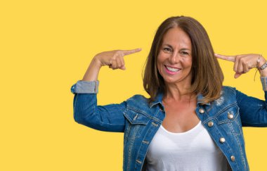 Güzel orta yaş kadın giyiyor rahat denim ceket izole üzerinde arka plan hem el parmak, harika bir fikir ya da düşünce, iyi hafıza ile baş gösteren gülen