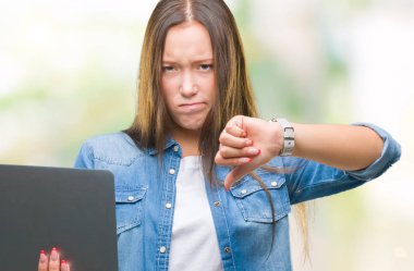 Kızgın yüz, eksi işareti aşağı antipati başparmak ile gösterilen, ret kavramı ile izole arka plan üzerinde dizüstü bilgisayar kullanan genç beyaz kadın