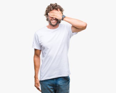 Yakışıklı İspanyol modeli adam gülümsüyor ve gözleri için sürpriz kapsayan yüz el ile gülüyor izole arka plan üzerinde. Kör kavramı.