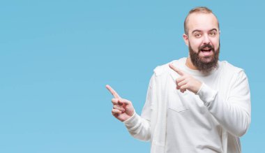Spor giyim gülümseyen ve iki elleri ve parmakları ile tarafına işaret kamera bakarak izole arka plan üzerinde giyen genç beyaz hipster adam.