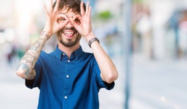 Dilini, parmaklarının arasından baktığını yapışmasını dürbün gibi ok jest yapıyor izole arka plan üzerinde gözlük takan yakışıklı delikanlı. Deli ifade.