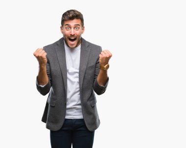 Genç yakışıklı iş adamı izole arka plan kutlama üzerinde şaşırttı ve başarı için kaldırdı kollarını açarak hayret ve gözleri açık. Kazanan kavramı.