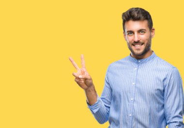 Mutlu yüz zafer işareti yaparken kameraya göz kırpıyor ile gülümseyen izole arka plan üzerinde genç yakışıklı adam. İki numaralı.