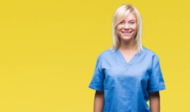 Genç güzel sarışın hemşire doktor kadın yüzünde mutlu ve güzel bir gülümseme ile izole arka plan yüzünden. Şanslı kişi.