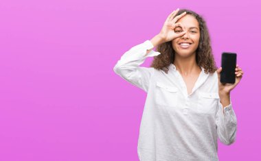 Mutlu yüz el parmaklarının arasından seyir göz üzerinde ok işaretiyle yapıyor gülümseyen ile akıllı telefon kullanan genç İspanyol kadın