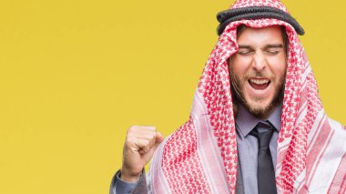 Genç yakışıklı Arap adam uzun saçlı keffiyeh izole arka kolları olan başarı için heyecan üzerinde giyen zafer kutluyor gülümseyen kaldırdı. Kazanan kavramı.