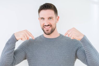 Yüzünde gülümseme ile kendinden emin görünüyorsun, kendini gururlu ve mutlu parmakları ile işaret izole arka plan üzerinde rahat kazak giyen genç yakışıklı adam.