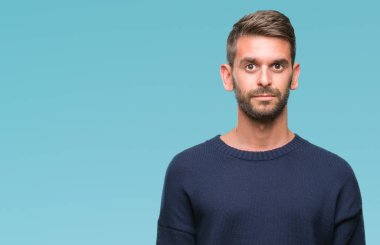 Yüzünde ciddi bir ifade ile izole arka plan üzerinde kış kazak giyen genç yakışıklı adam. Basit ve doğal kameraya bakıyor.