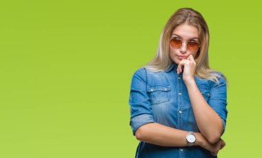 Genç kafkas kadın elle çene düşünme hakkında soru, dalgın ifade izole arka plan üzerinde güneş gözlüğü takıyor. Düşünceli yüzüyle gülümsüyor. Şüphe kavramı.